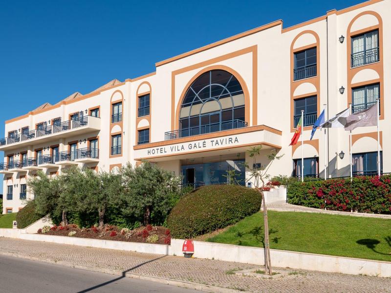 Modernes, dreistöckiges Hotelgebäude mit Balkonen, großen Fenstern und gepflegtem Vorgarten.