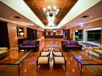 Großer Raum mit orangem Boden, zwei violetten Sofas, weißen Sesseln und Glas-Couchtischen.