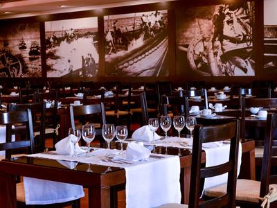 Edles Restaurant mit Holzmöbeln, weißen Tischdecken, Weingläsern und großen Schwarz-Weiß-Fotos an der Wand.