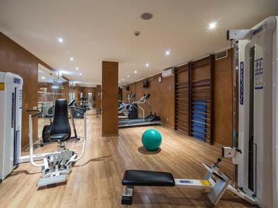 Moderner Fitnessraum mit Holzboden, Geräten, Gymnastikball und gut beleuchtetem Raum.