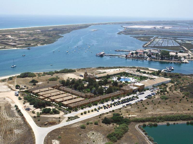 Luftaufnahme eines Hafens mit Gebäuden, Booten, Wasserwegen und weitläufigem flachem Gelände.