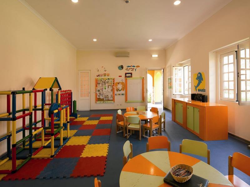 Luftaufnahme einer Küstenanlage mit Bootshafen, Schwimmbad und umgeben von Bäumen und Parkplätzen.