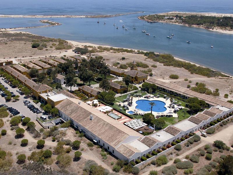 Luftaufnahme eines rechteckigen Resorts mit Pool, umgeben von trockenem Gelände nahe eines Flusses.