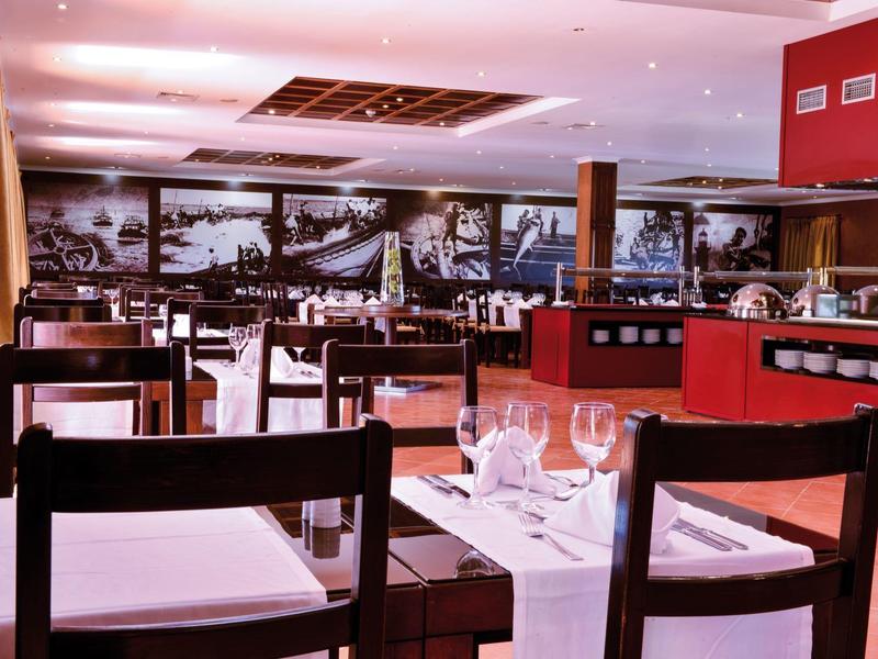 Elegantes Restaurant mit dunklen Holzstühlen, weißen Tischdecken und großer schwarz-weißer Wanddekoration.