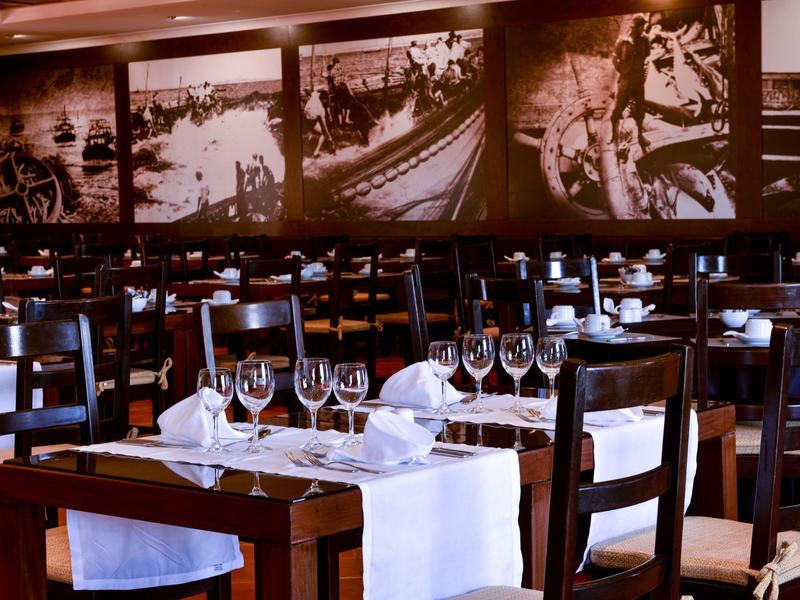 Edles Restaurant mit Holzmöbeln, weißen Tischdecken, Weingläsern und großen Schwarz-Weiß-Fotos an der Wand.