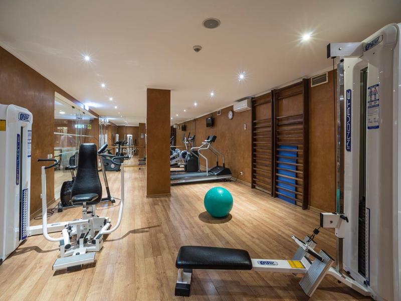 Moderner Fitnessraum mit Holzboden, Geräten, Gymnastikball und gut beleuchtetem Raum.