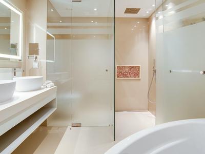 Modernes Badezimmer mit weißen Sanitäranlagen, Glasdusche und großer Badewanne.