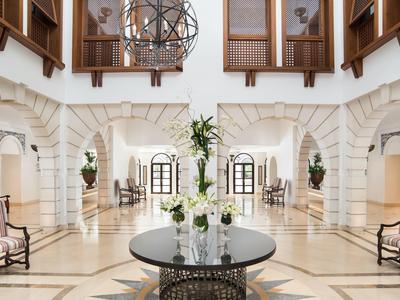 Heller, eleganter Hotellobby mit Rundtisch, Sesseln und hohen Decken mit Kronleuchtern.