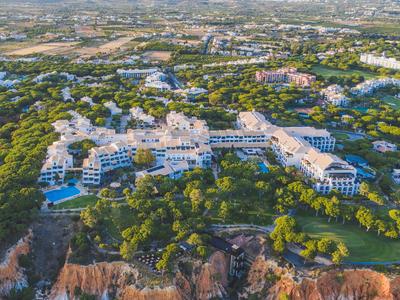 Luxuriöses Resort mit Pools umgeben von Bäumen und Klippen an der Küste.