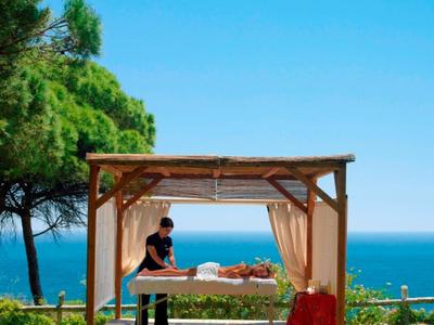 Massage im Freien unter einem Holzpavillon mit Blick auf das Meer.