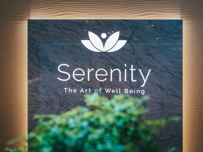 Dunkle Wand mit weißem Serenity-Logo und grünem Pflanzenbereich im Vordergrund.