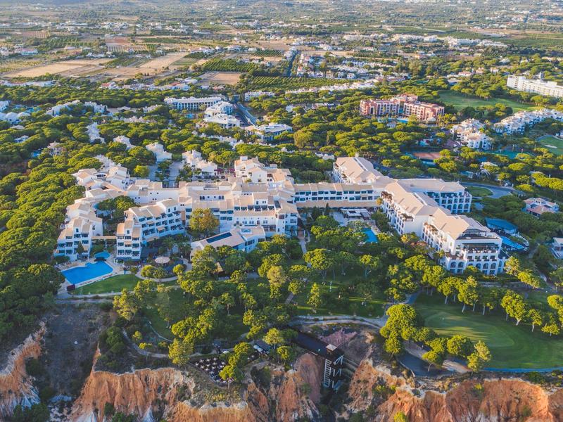 Luxuriöses Resort mit Pools umgeben von Bäumen und Klippen an der Küste.