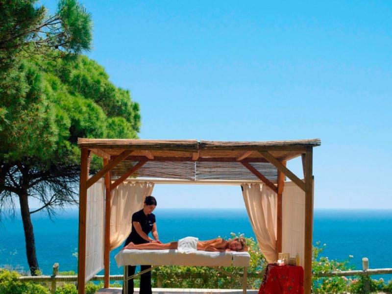 Massage im Freien unter einem Holzpavillon mit Blick auf das Meer.