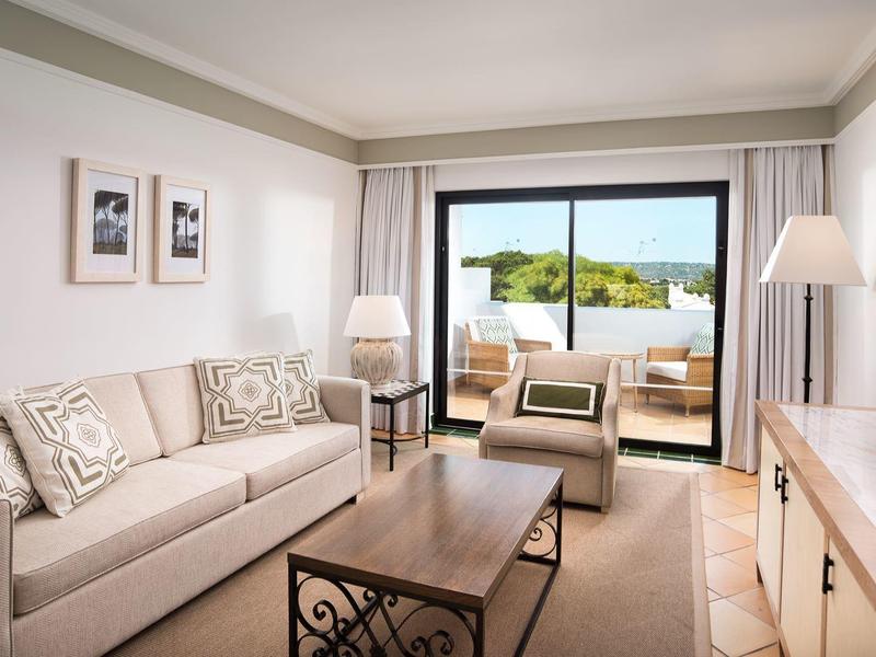 Geräumiges Wohnzimmer mit Sofa, Sesseln und Zugang zu einer Terrasse mit Blick auf die Natur.