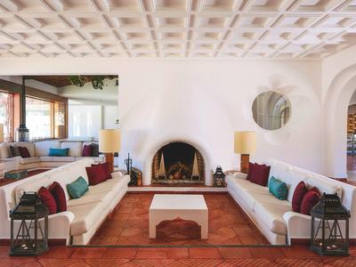 Heller Wohnraum mit weißen Sofas, bunten Kissen, rundem Kamin und Terrakottaboden.