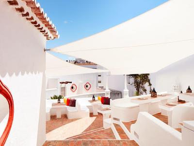 Gemütliche weiße Terrasse mit rot-weißer Dekoration und offenem blauen Himmel.