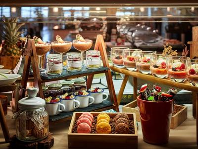 Vielfältiges Dessertbuffet mit bunten Macarons, Kuchen, Obst und kleinen Gläsern mit Süßspeisen.