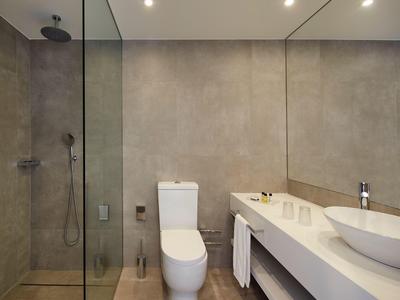 Moderner Badezimmerbereich mit bodentiefer Glasdusche, weißem WC und Waschtisch mit runder Aufsatzschüssel.