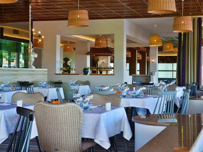 Elegantes Restaurant mit weiß gedeckten Tischen, Holzmöbeln und warmem Licht, gemütliche Atmosphäre.