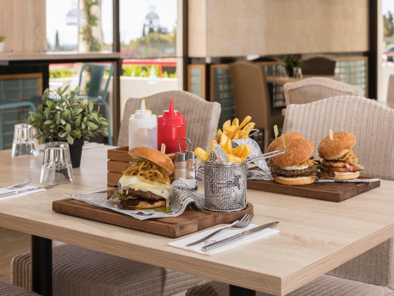 Tisch im Restaurant mit Burgern, Pommes und Getränken in einem hellen, gemütlichen Raum.