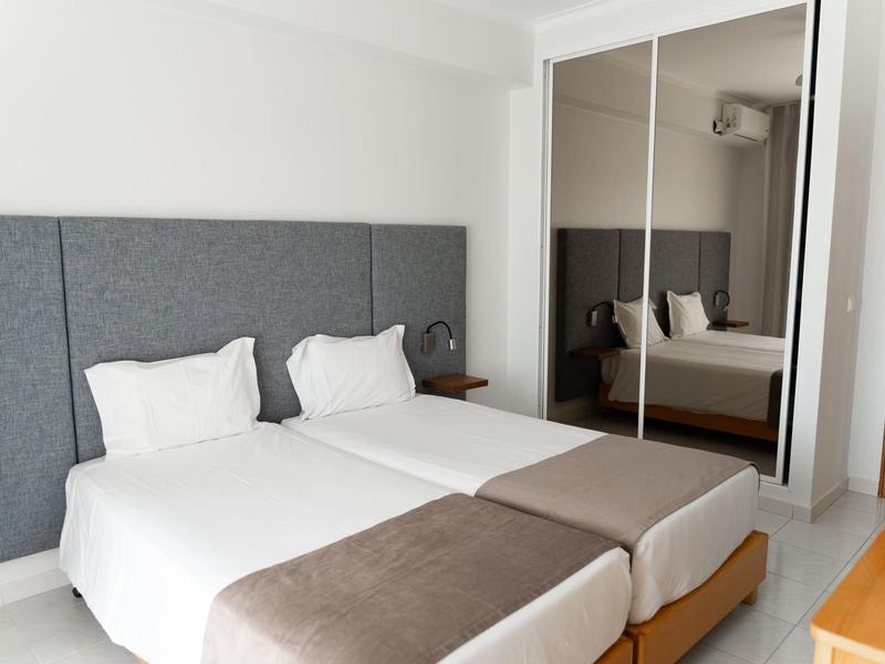 Helles Hotelzimmer mit zwei Einzelbetten und großen Spiegeln an der Wand.