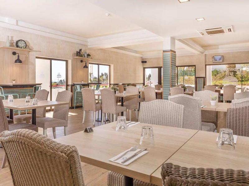 Helles, modernes Restaurant mit geflochtenen Sesseln und großen Fenstern.