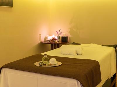 Ein ruhiger Raum mit einer Massageliege, warmem Licht und einem Augenstein auf einem Tablett.