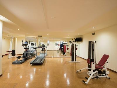 Großer, heller Fitnessraum mit Holzfußboden, Cardio- und Kraftgeräten und Spiegelwand.