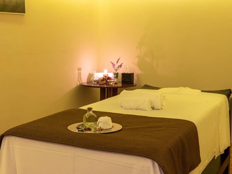 Ein ruhiger Raum mit einer Massageliege, warmem Licht und einem Augenstein auf einem Tablett.