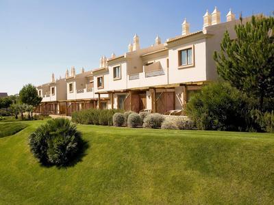 Case a schiera con prato verde ben curato e cespugli sotto un cielo soleggiato.