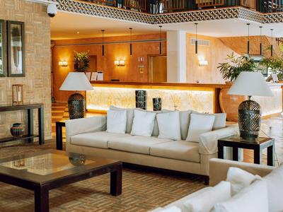 Großzügiges Wohnzimmer mit weißen Sofas, Holztischen und warmem Licht in modernem Ambiente.