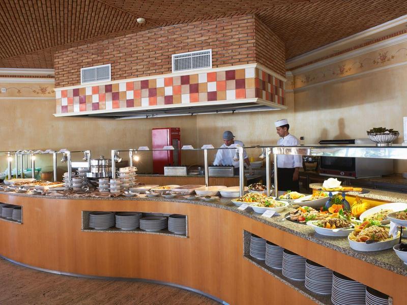 Buffet mit vielfältigen Speisen auf gebogenem Holztresen in hellem, modernem Restaurant.