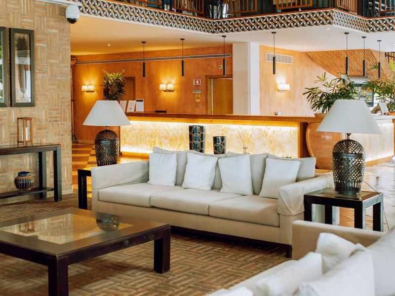 Großzügiges Wohnzimmer mit weißen Sofas, Holztischen und warmem Licht in modernem Ambiente.