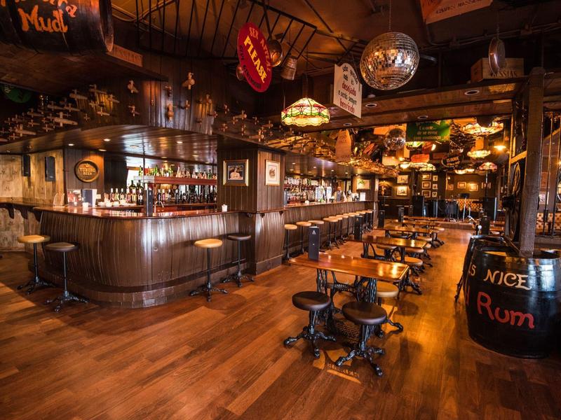 Przytulne wnętrze drewnianego baru z stołami, krzesłami i oświetlonym barem.