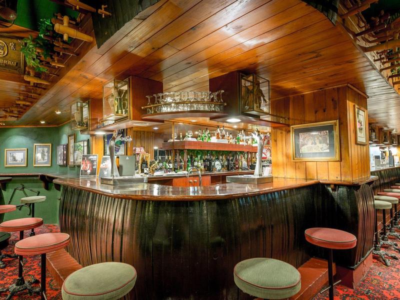 Przytulny drewniany bar z hokerami i przytłumionym oświetleniem.