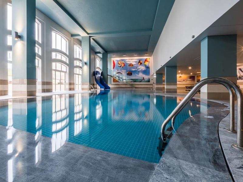 Elegancki wewnętrzny basen z dużymi oknami i artystycznym muralem.