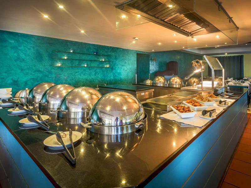 Bufet z gorącymi potrawami pod stalowymi pokrywami na błyszczącym blacie w restauracji.