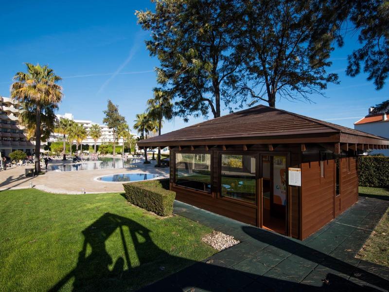 Drewniany domek obok basenu hotelowego pod jasnym niebem.