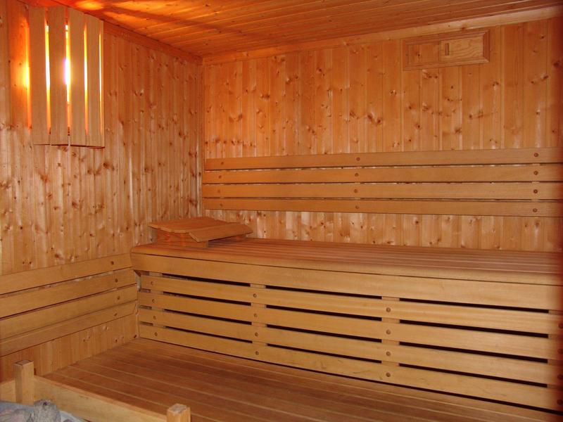 Wnętrze przytulnej sauny drewnianej z piętrowymi ławkami i miękkim oświetleniem.