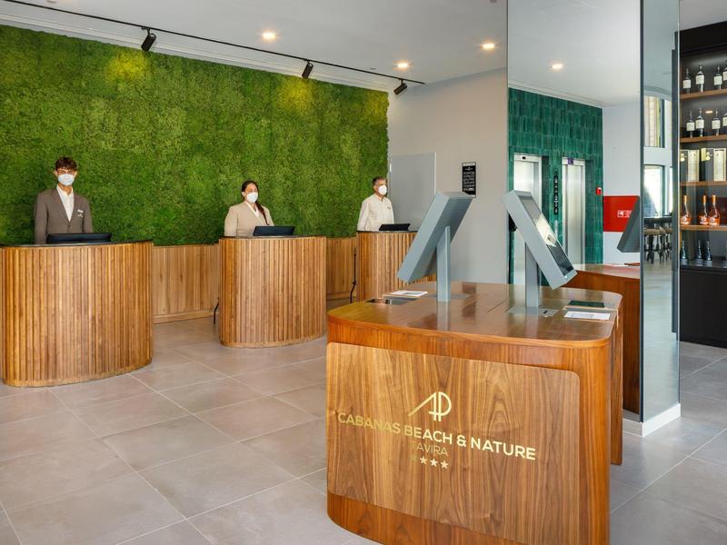 Receptiegebied van het hotel met houten balies en een groene mosmuur.