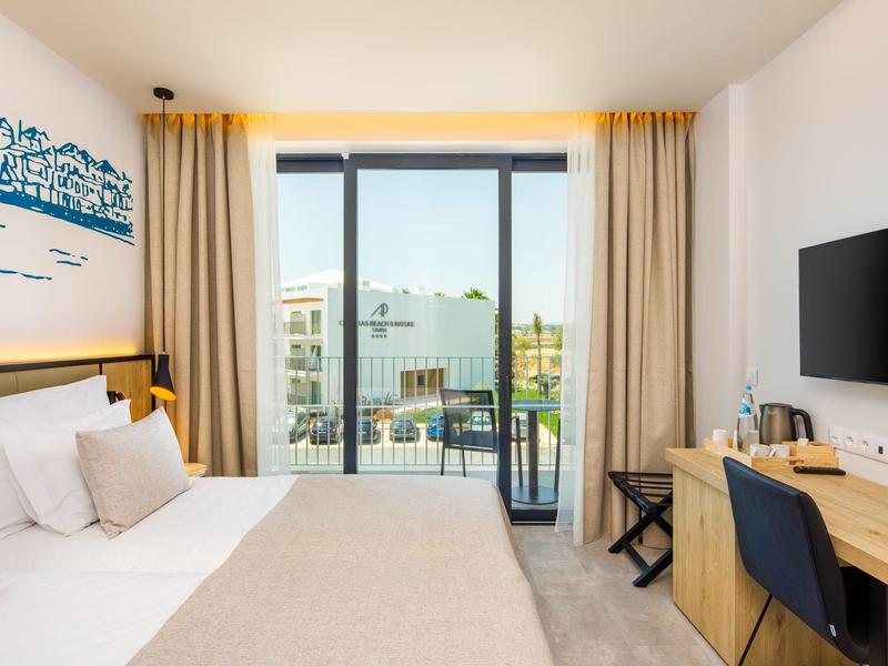 Modern hotelkamer met tweepersoonsbed, balkon en uitzicht op de Overwinningszuil en stad.