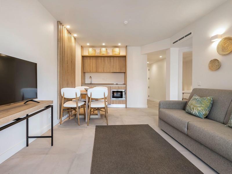 Nowoczesny salon z sofą, telewizorem, stołem jadalnym i otwartą kuchnią.