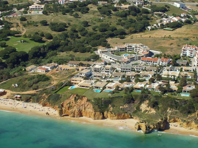 Hotel nadmorski z piaszczystą plażą, klifami i zalesionymi wzgórzami w tle