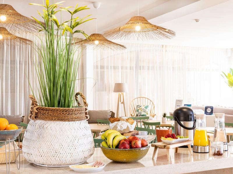 Jasne bufet śniadaniowy z świeżymi owocami, sokiem i dekoracyjnymi roślinami w nowoczesnym hotelu.