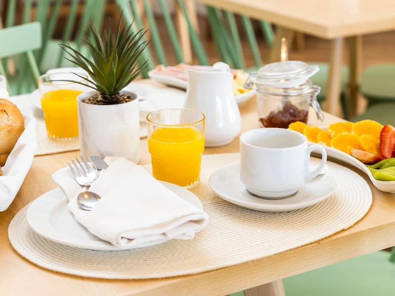 Miejsce na śniadanie z sokiem pomarańczowym, kawą, chlebem i świeżymi owocami na jasnym stole.