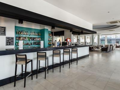 Moderne hotelbar met zwarte krukken en een ruime zithoek met grote ramen.