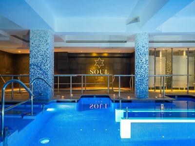 Overdekt zwembad met blauwe verlichting en decoratieve pilaren in een hotel spa-ruimte.