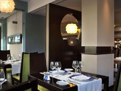 Elegant hotelrestaurant met witte tafelkleden, groene stoelen en sfeerverlichting.