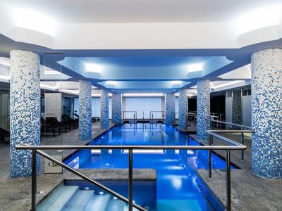 Binnenzwembad met blauw verlicht water en decoratieve zuilen in een modern hotel.