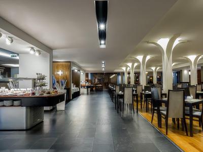 Ruim en modern restaurantinterieur met tafels, stoelen, buffet en bogen aan het plafond.